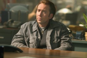 Nicolas Cage sits at a desk.